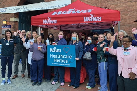 Staff at Pennsylvania Hospital pose outside in front of a Wawa tent and holding a “Wawa Healthcare Heroes” sign.